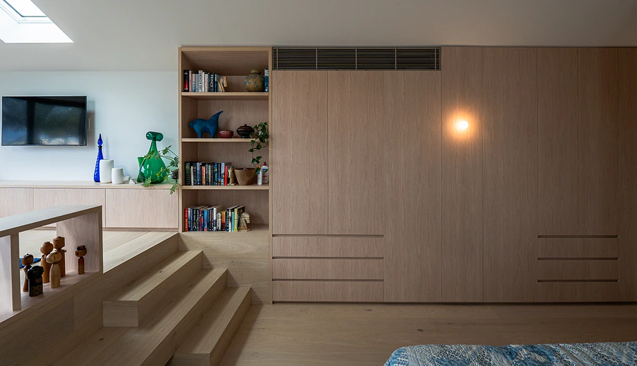 Built-in timber wardrobe wall with integrated bookshelves in a bedroom