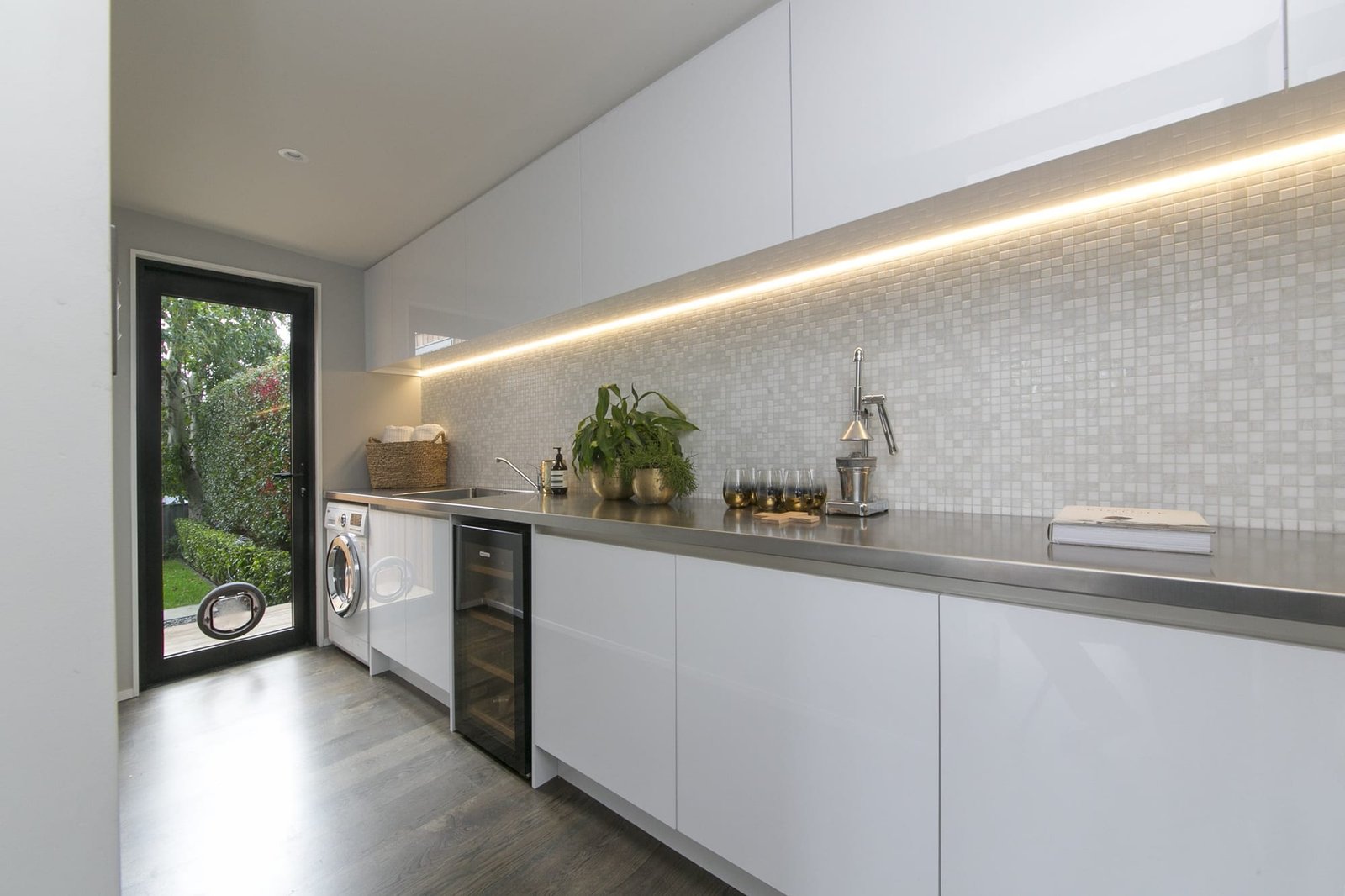 Modern white laundry with stainless benchtop and LED strip lighting